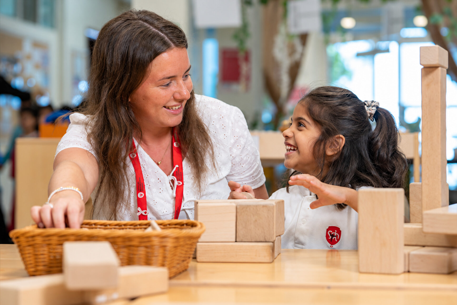 Affordable international schools in Dubai: teacher and young student playing with wooden blocks
