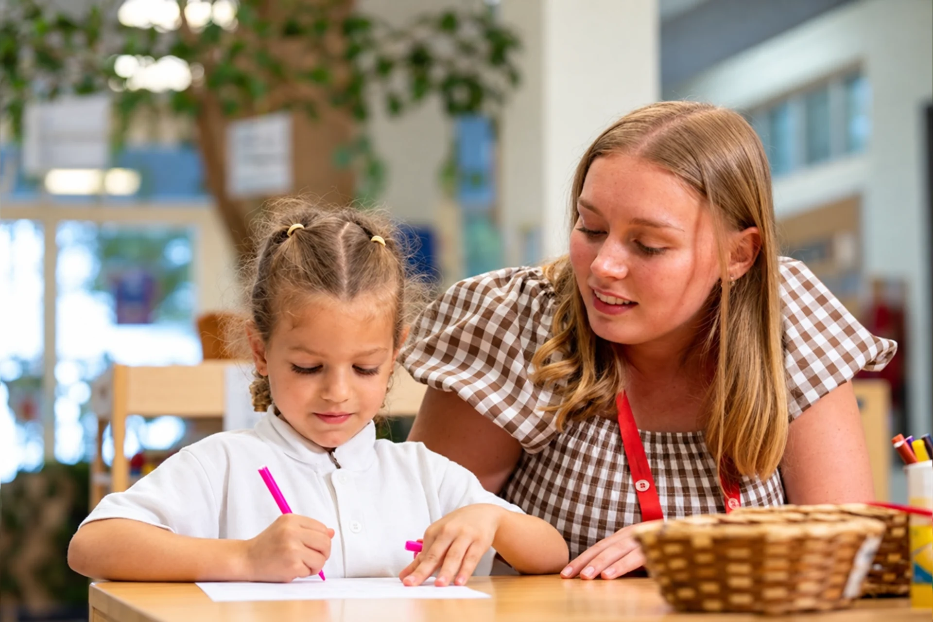 British vs American curriculum in UAE: teacher supporting a young student with writing